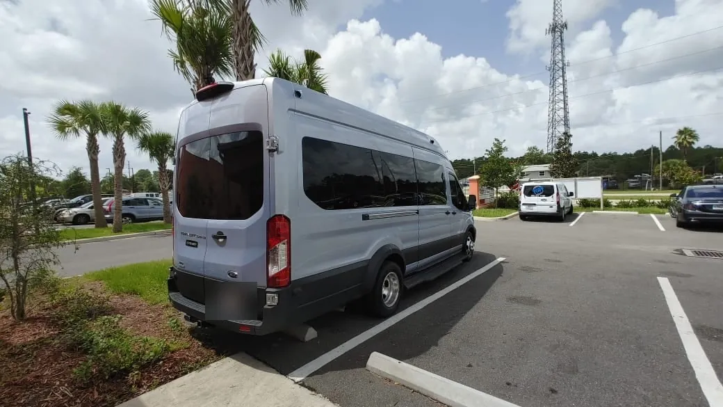 Silver Ford Transit passenger van with dark rear glass