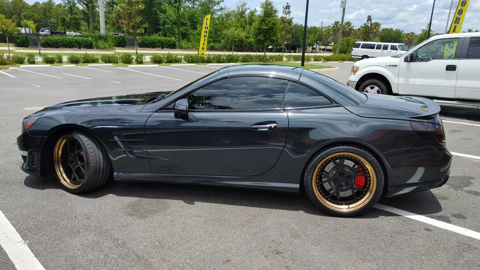Black Mercedes SL AMG with gold wheels and dark side window tint
